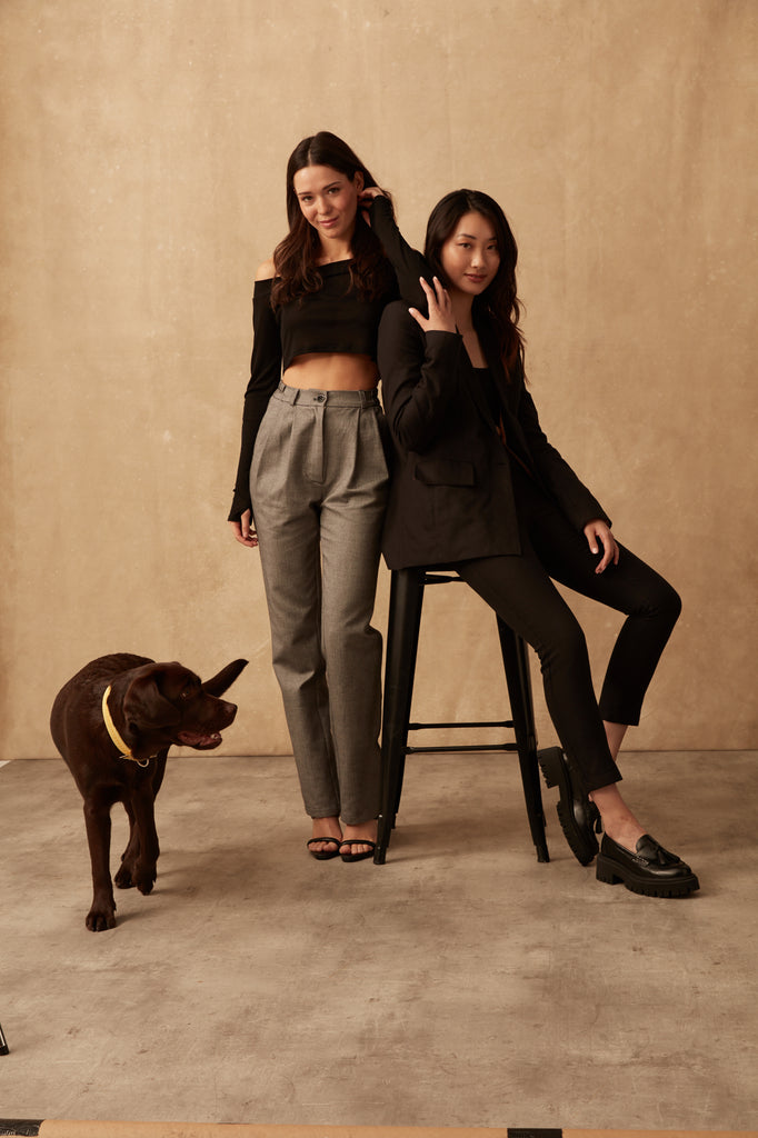 Two of our models posing wearing our Tencel and Organic Cotton wardrobe staples. One model is sitting on a stool, with the other model leaning on her. Also featuring is our Labrador Cleo, looking cute