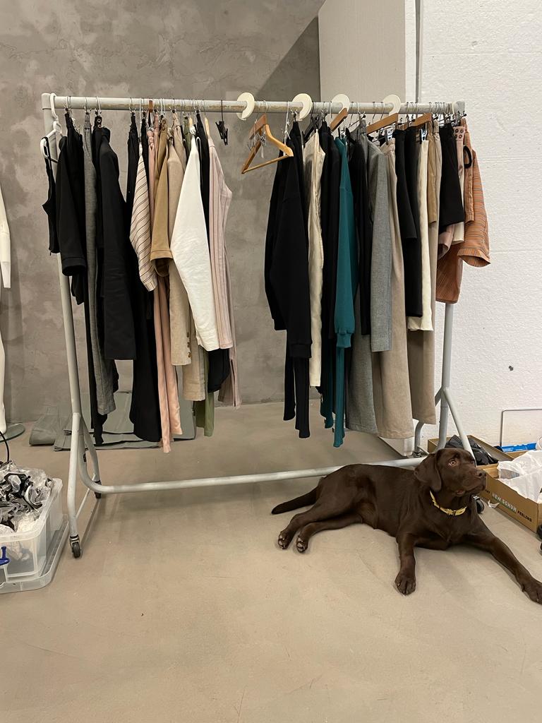 Clothes rail with some of our sustainable minimalist clothes, it's in the photo studio and sitting in front is our dog, Cleo. She is looking cute